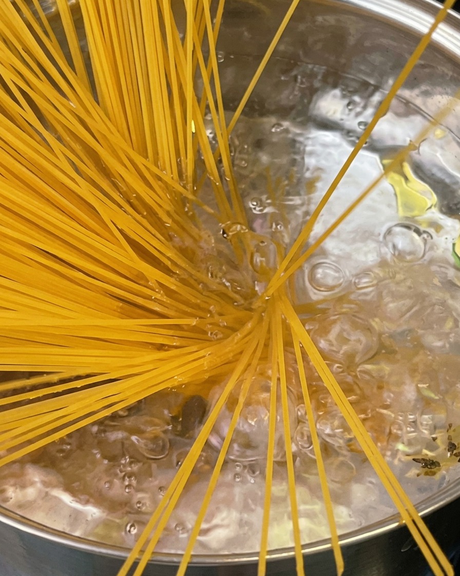 茹で上がったパスタをトングで引き上げている様子。