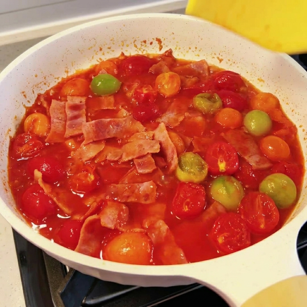 トマトとベーコンのソースにスライスチーズが溶けている様子。