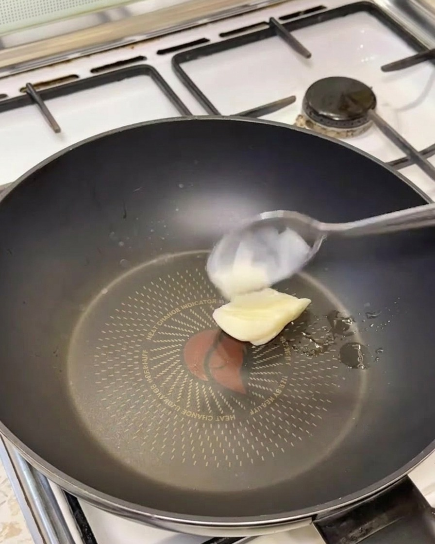 熱した黒いフライパンの上で白いラードが溶けている様子