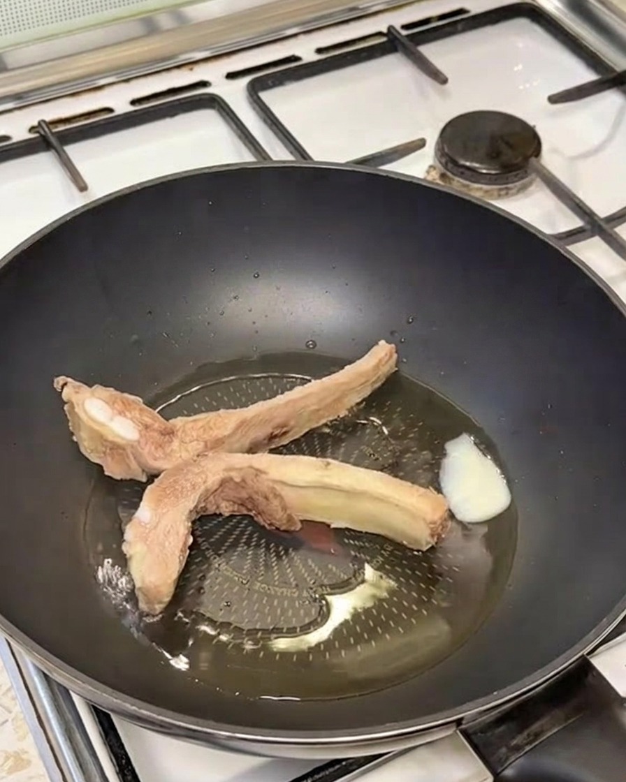 溶かしたラードが入ったフライパンで豚スペアリブがきつね色に焼けている様子