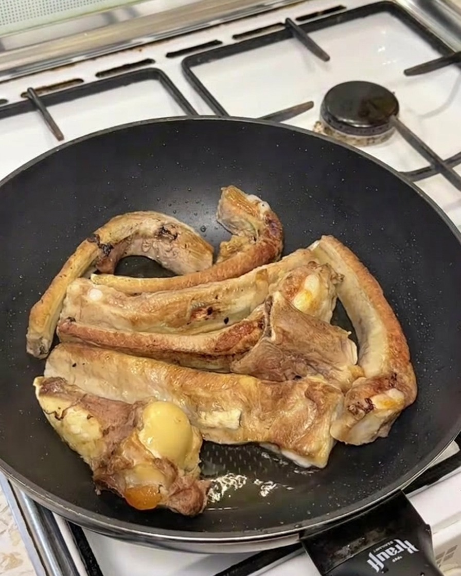 こんがり焼けたスペアリブが入ったフライパンに熱湯を注ぎ、湯気が立ち上っている様子