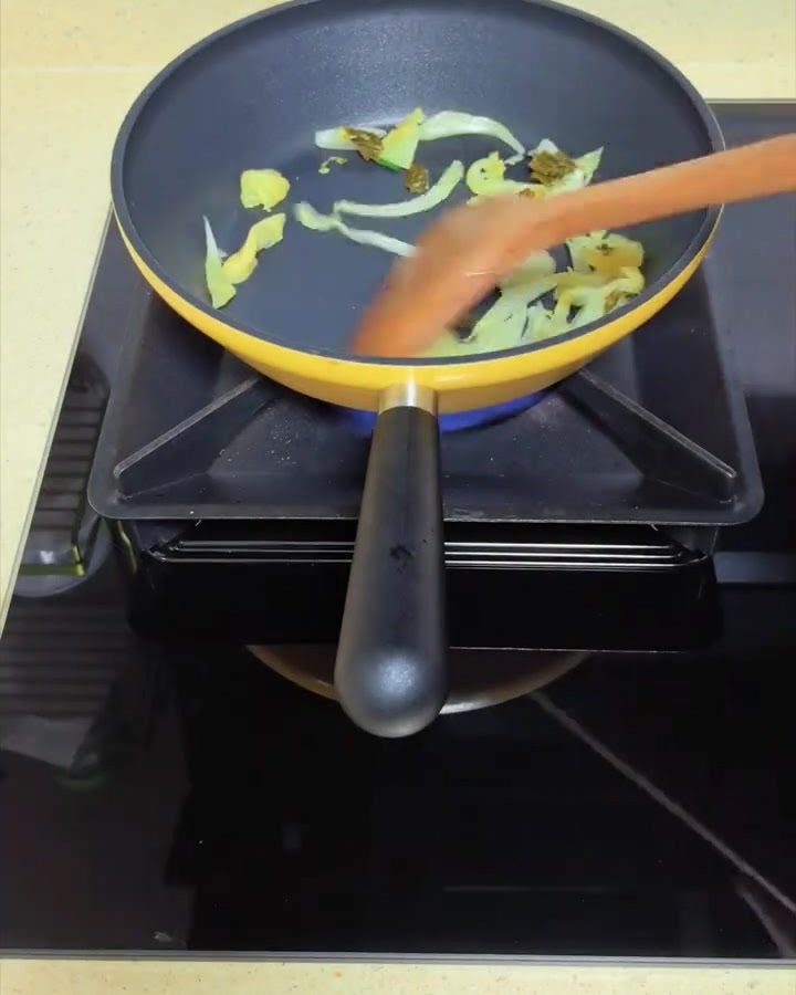 フライパンで高菜を木べらで炒めている様子