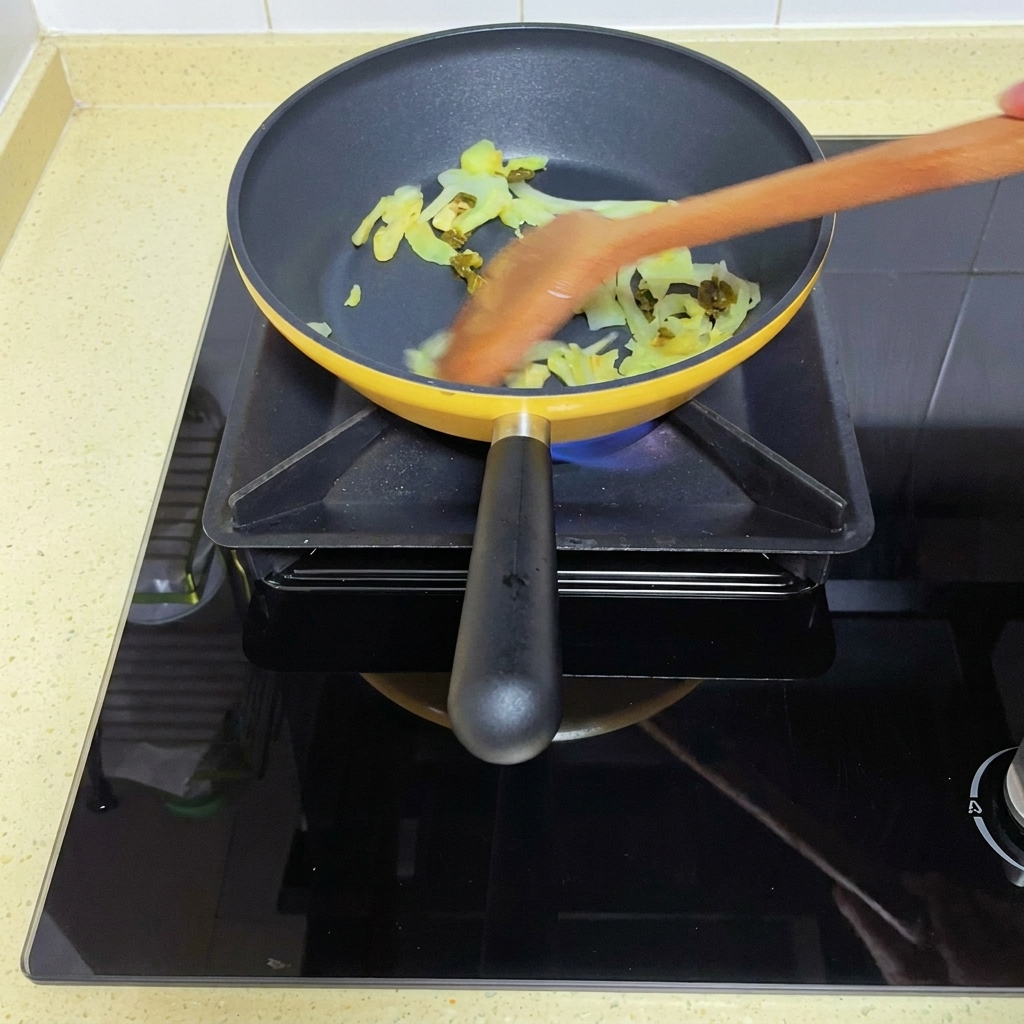 炒めた高菜に角切りトマトを加えている様子
