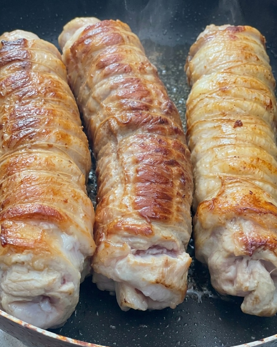 フライパンでこんがりと焼き色がつき、香ばしそうに焼けている巻いた豚バラ肉。
