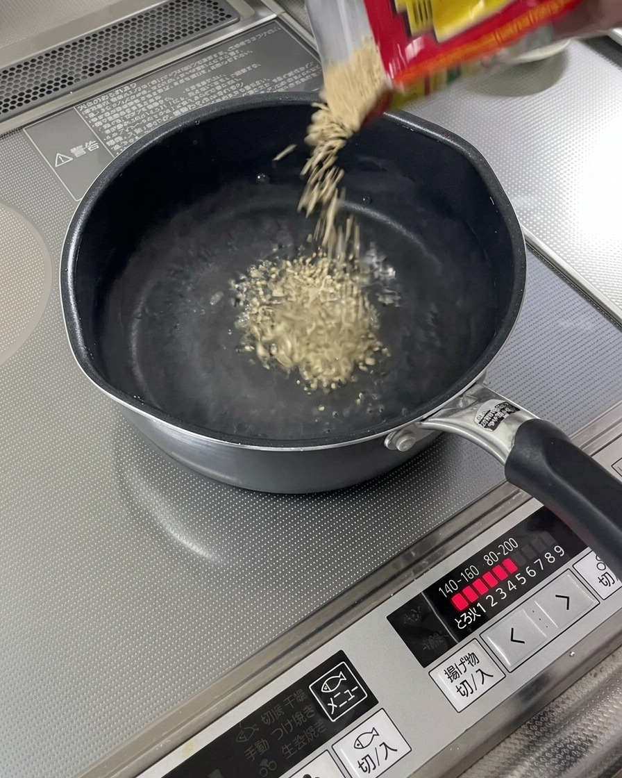 沸騰したスープにいりごまが振り入れられている様子。