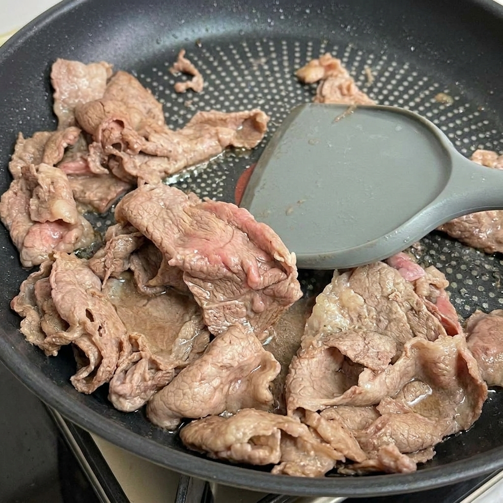 フライパンから取り出された、半生状態の柔らかそうな牛肉。