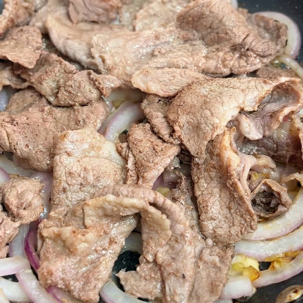 フライパンの具材に照り焼きソースを回し入れている瞬間。
