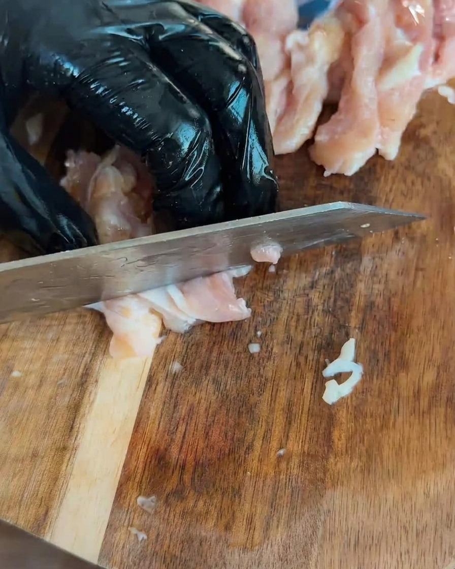 木製のまな板に並べられた、一口サイズにカットされた生の鶏肉。