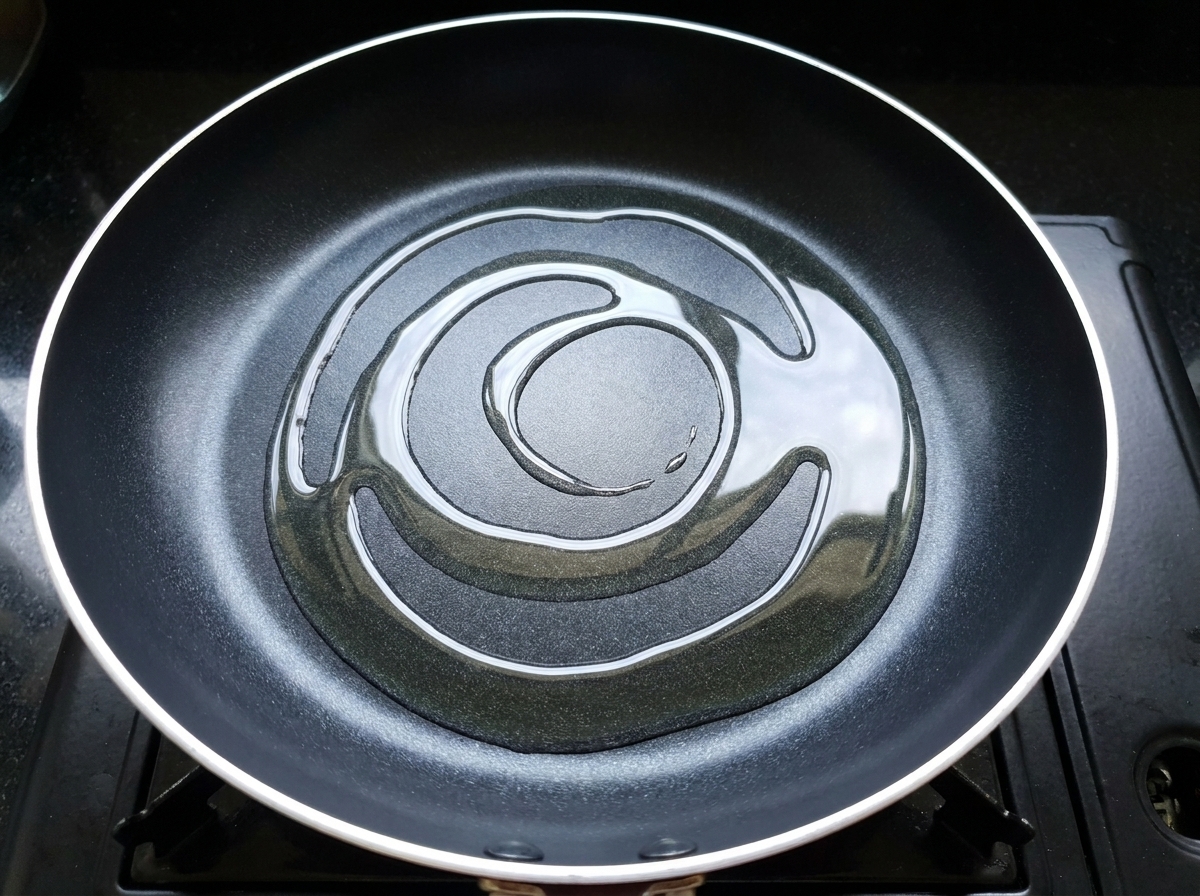 熱した油をひいたフライパンに、漬け込んだ鶏肉を広げている様子。