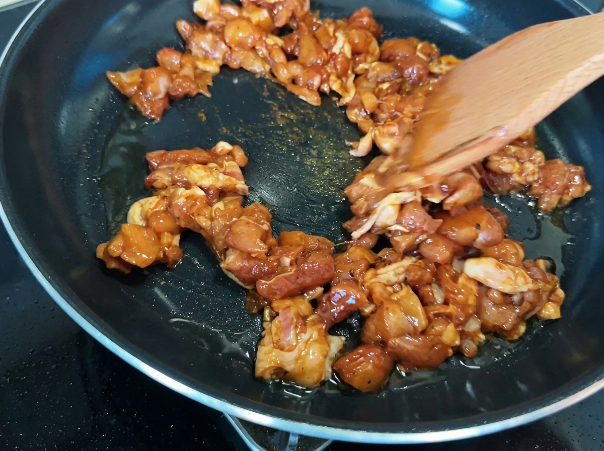 フライパンの中で鶏肉がこんがりと黄金色に炒められている様子。
