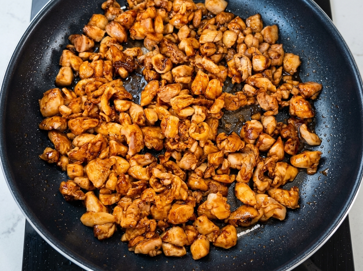 焼いた鶏肉の中に刻んだ長ネギを加えている様子。