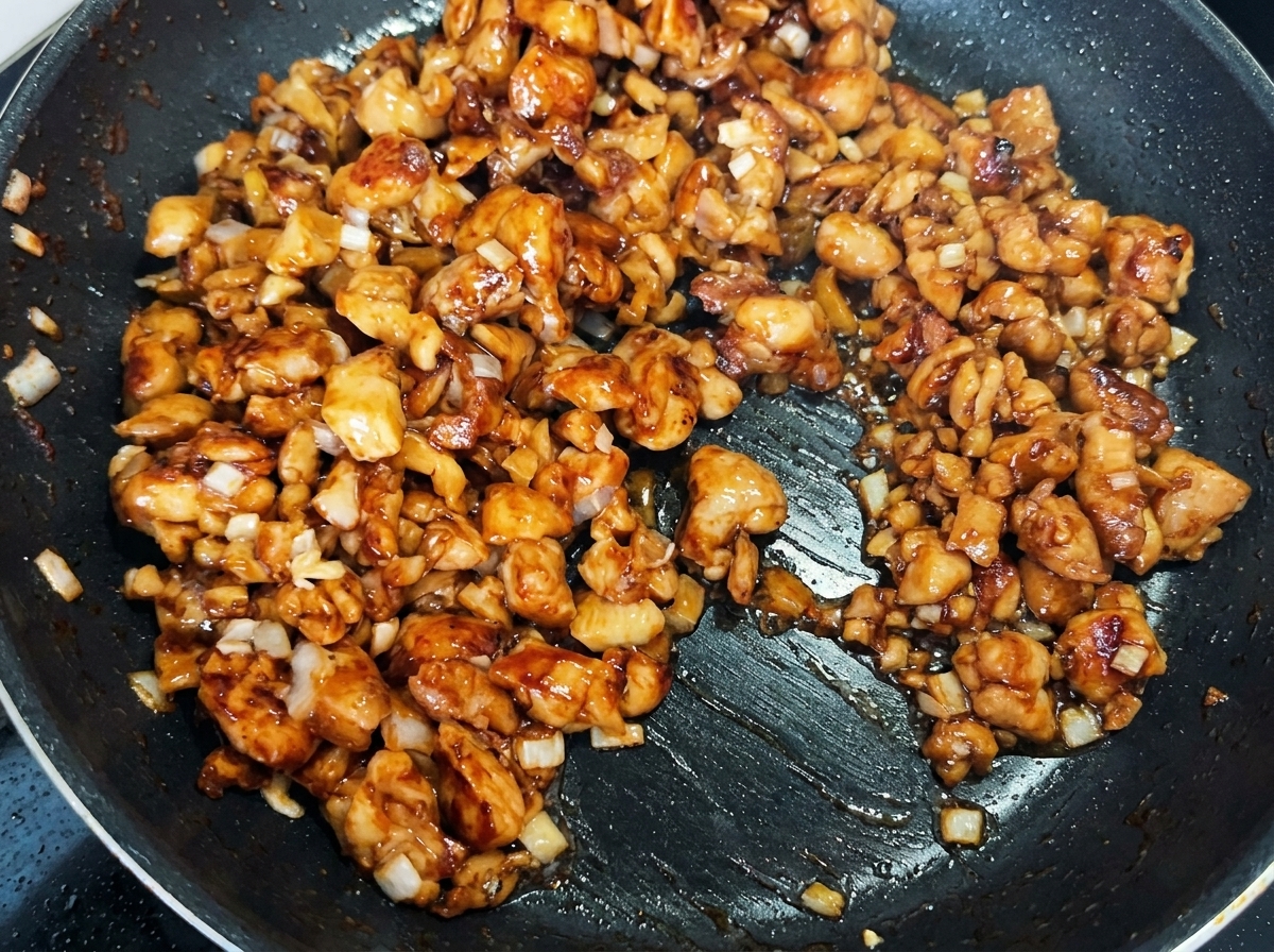鶏肉とネギに高菜漬けを加えて混ぜ合わせている様子。