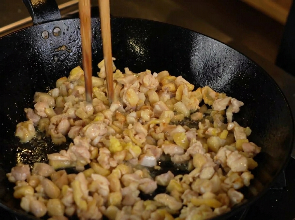 焼き色がついた鶏肉の入ったフライパンに、すりおろした生姜を加えている様子。