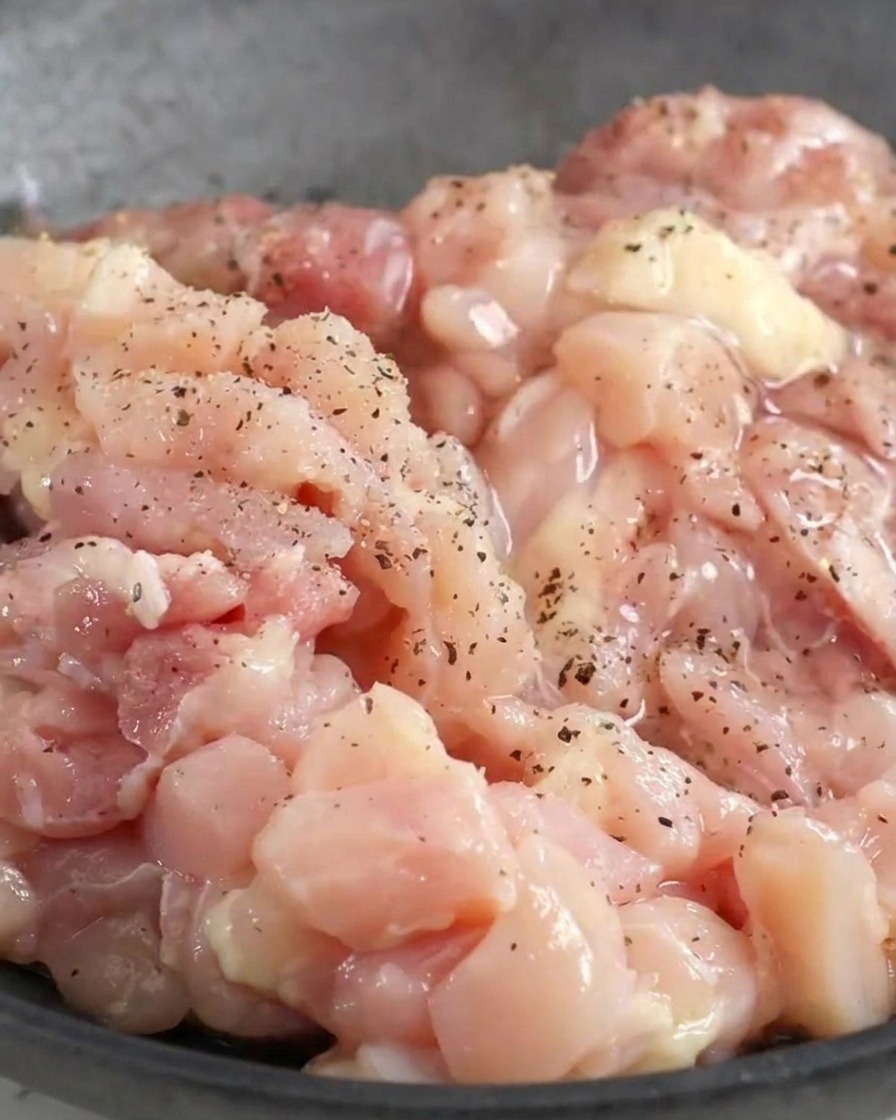 ボウルに入った鶏肉に黒こしょうと液体調味料を絡めている様子。