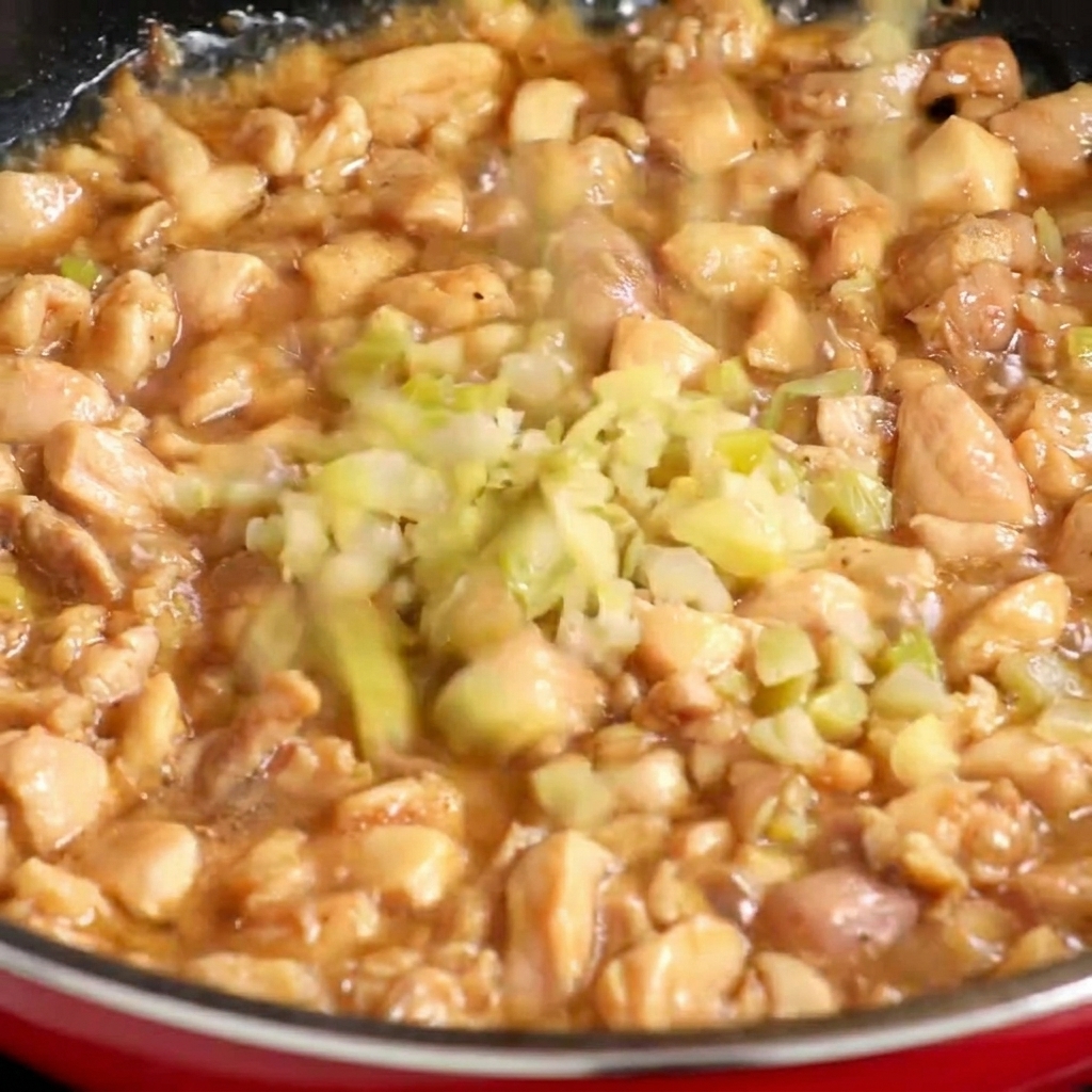 鶏肉に火が通り始めたフライパンに、細かく刻んだザーサイを加えている様子。