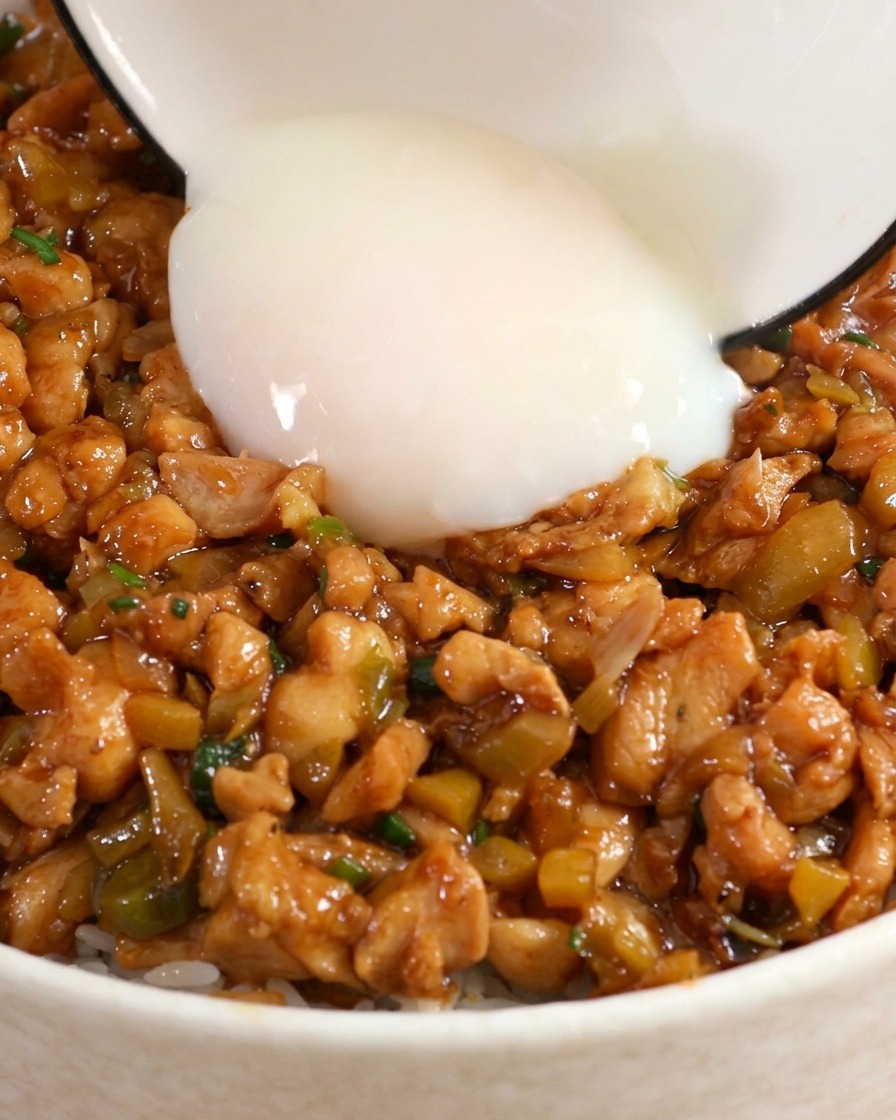 鶏そぼろ丼の中央のくぼみに、温泉卵をそっとのせている様子。