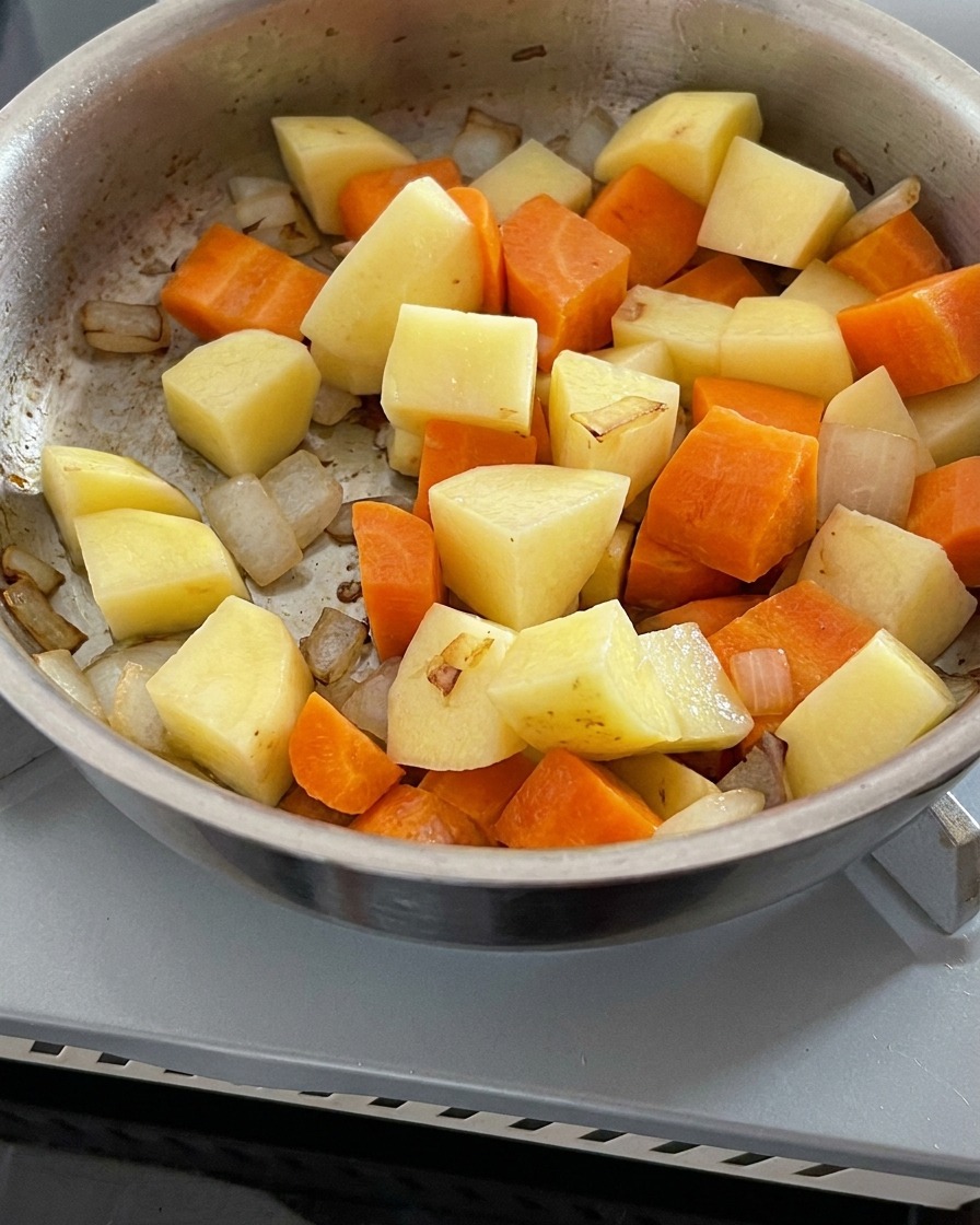 炒めた野菜が入った鍋に水を注いでいる様子。