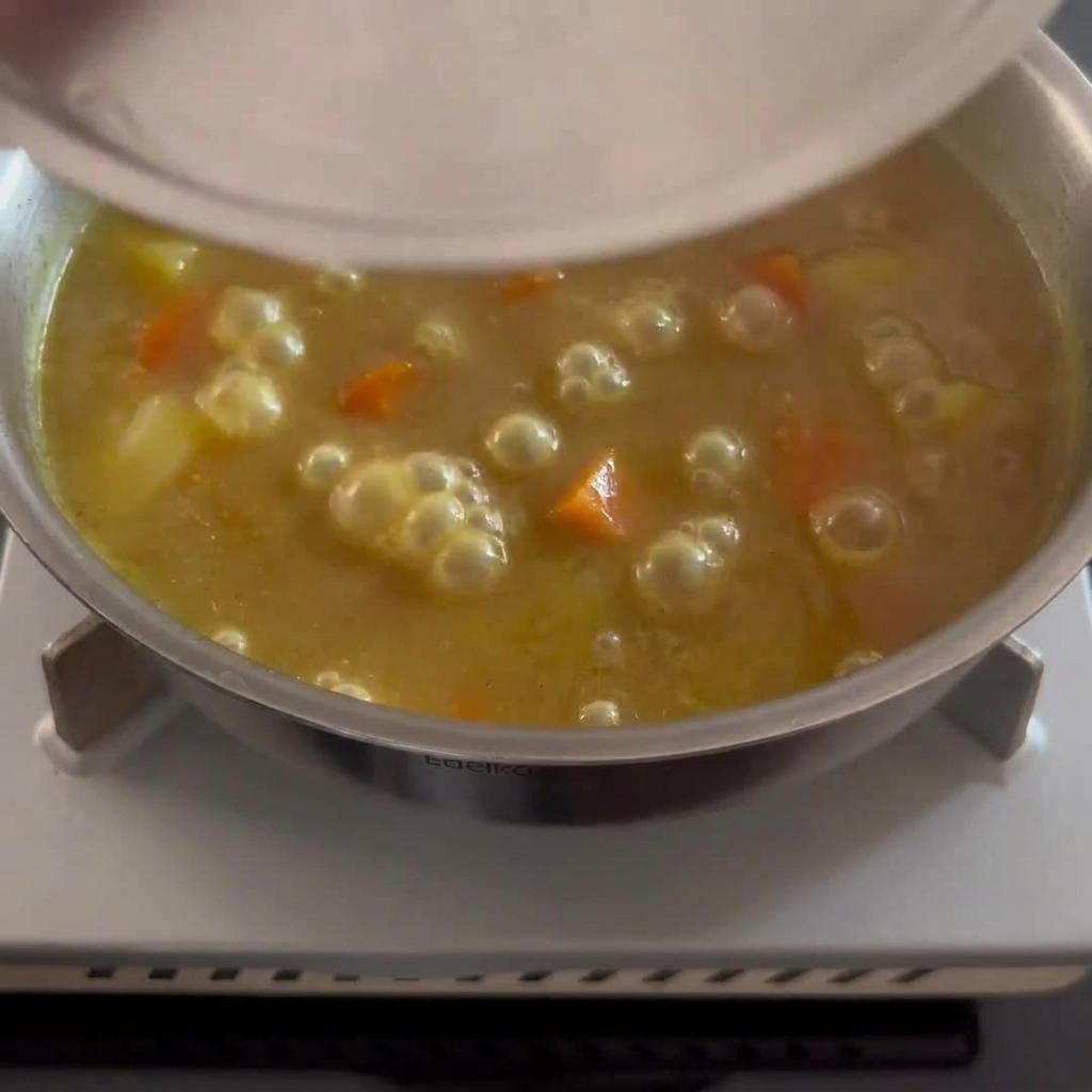 じゃがいもとにんじんがゴロゴロ入った濃厚なカレーをかき混ぜている様子。