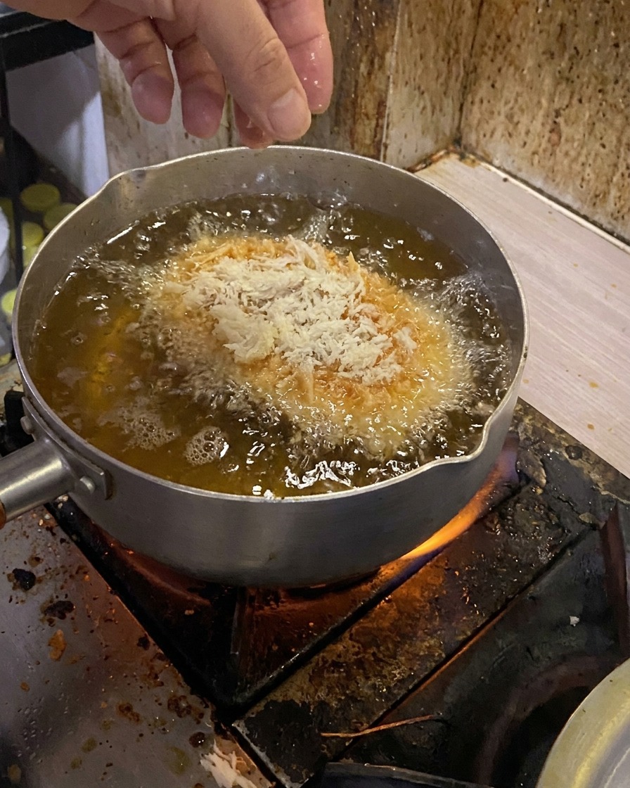 衣をつけた豚肉を、高温の油に静かに入れている様子。