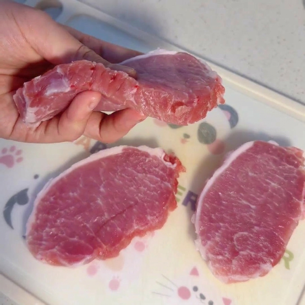 まな板の上に置かれた生の豚ヒレ肉の厚切り肉。