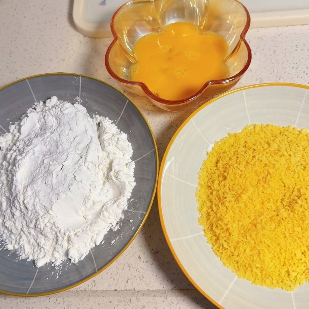 豚肉の切り身を片栗粉の入った皿に押し当てている様子。