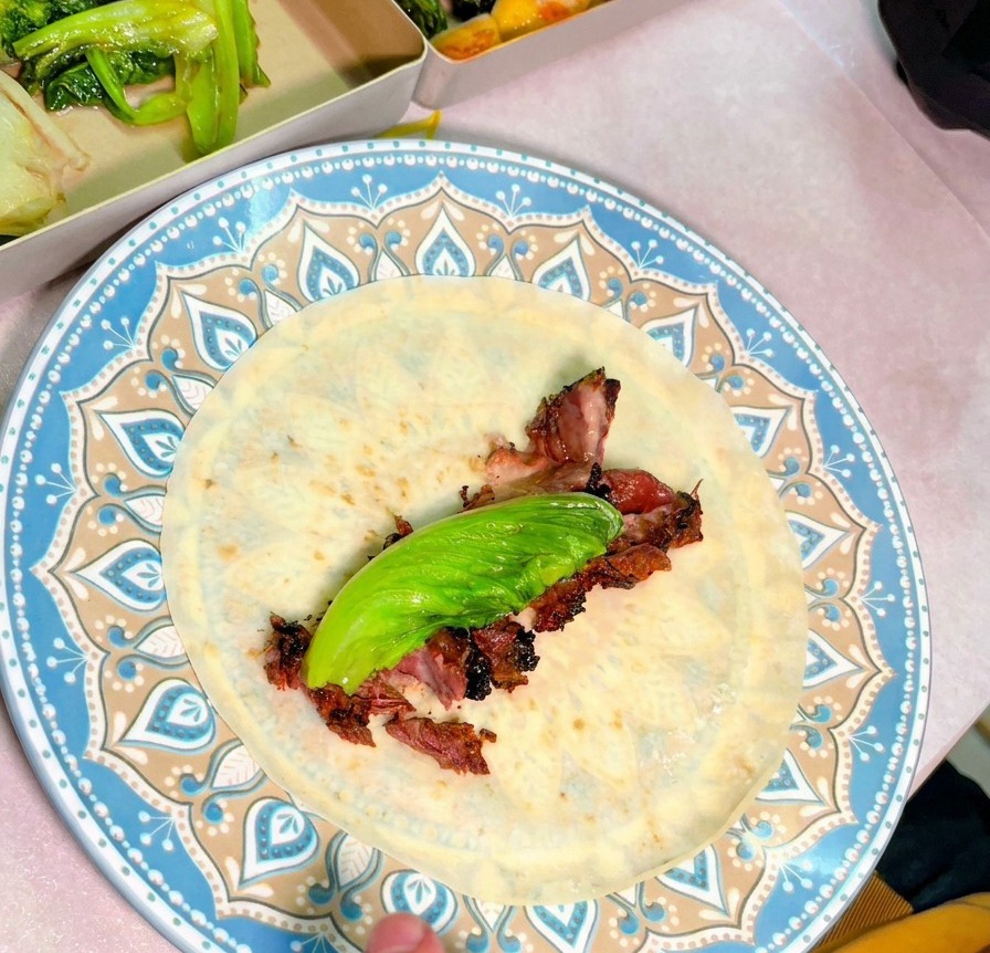 お皿の上に広げたトルティーヤに、スライスした肉と新鮮な野菜が盛り付けられている俯瞰写真。