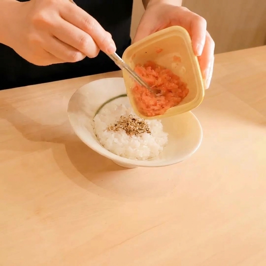 白ごまを振ったご飯の上に、細かくたたいたマグロをのせている様子。