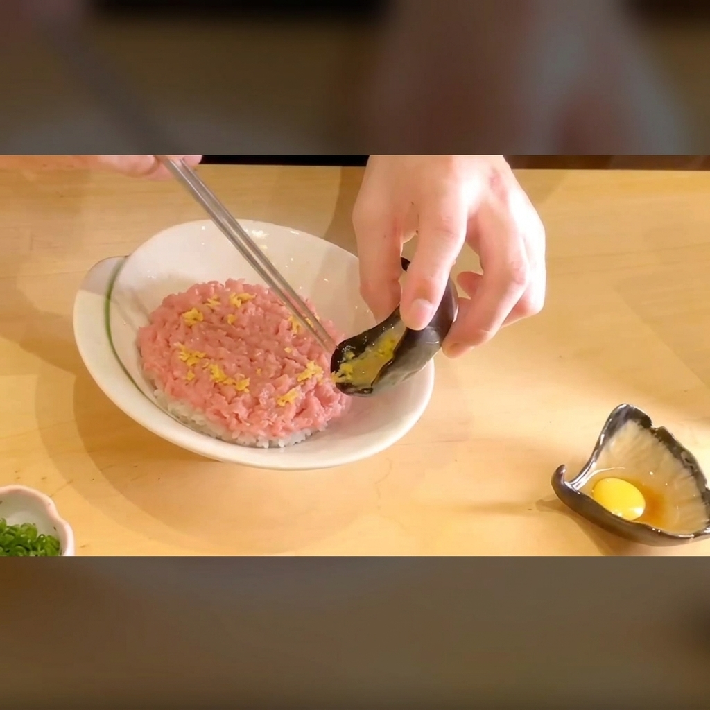 マグロの上に、細かく刻んだ鮮やかな黄色いたくあんを添えているアップ画像。