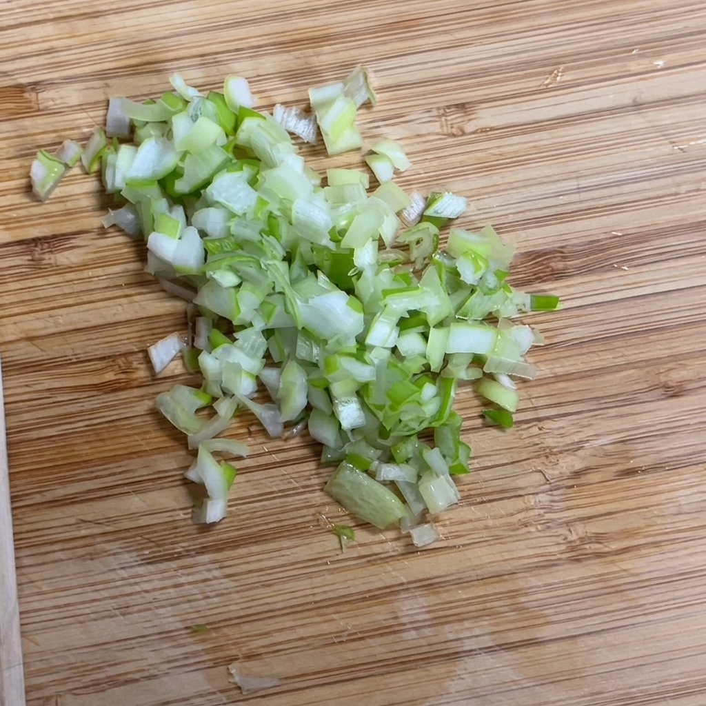 木製のまな板の上で細かく刻まれる新鮮な青ネギ。