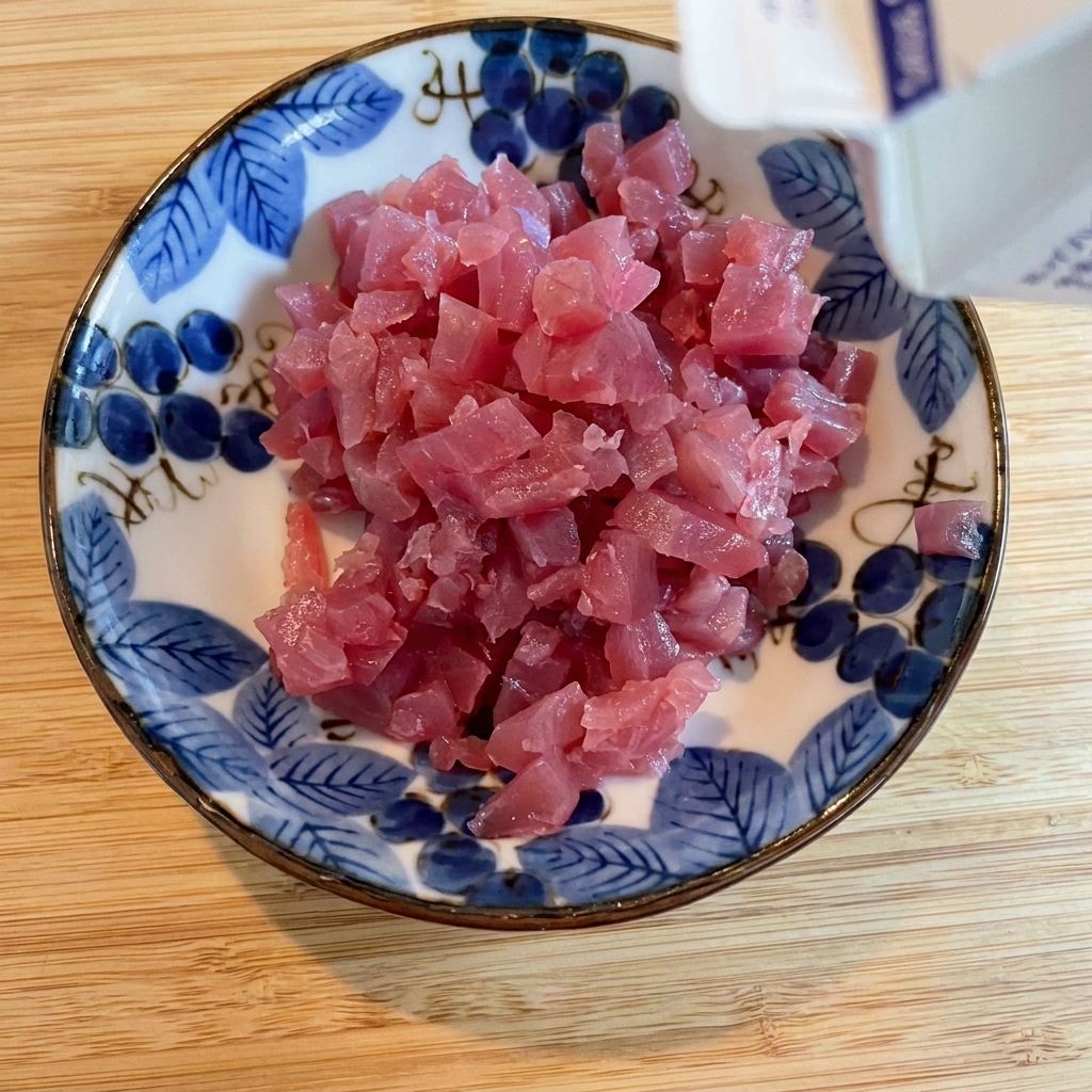 器に入れた角切りマグロに醤油を回しかけている様子。