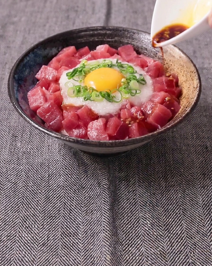 醤油とわさびの合わせ調味料を、盛り付けた丼にかけている様子。