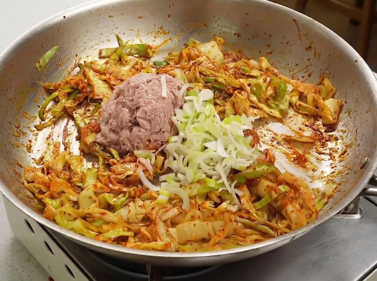 タレが絡んだキャベツの上に、油を切ったツナと青ねぎを乗せている様子。