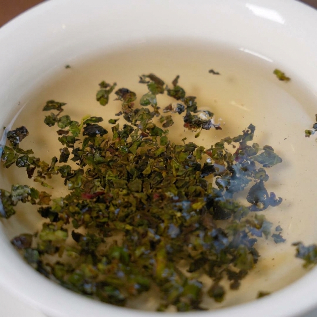 熱湯が入った白いボウルの中で開き、色づき始める鉄観音茶の茶葉