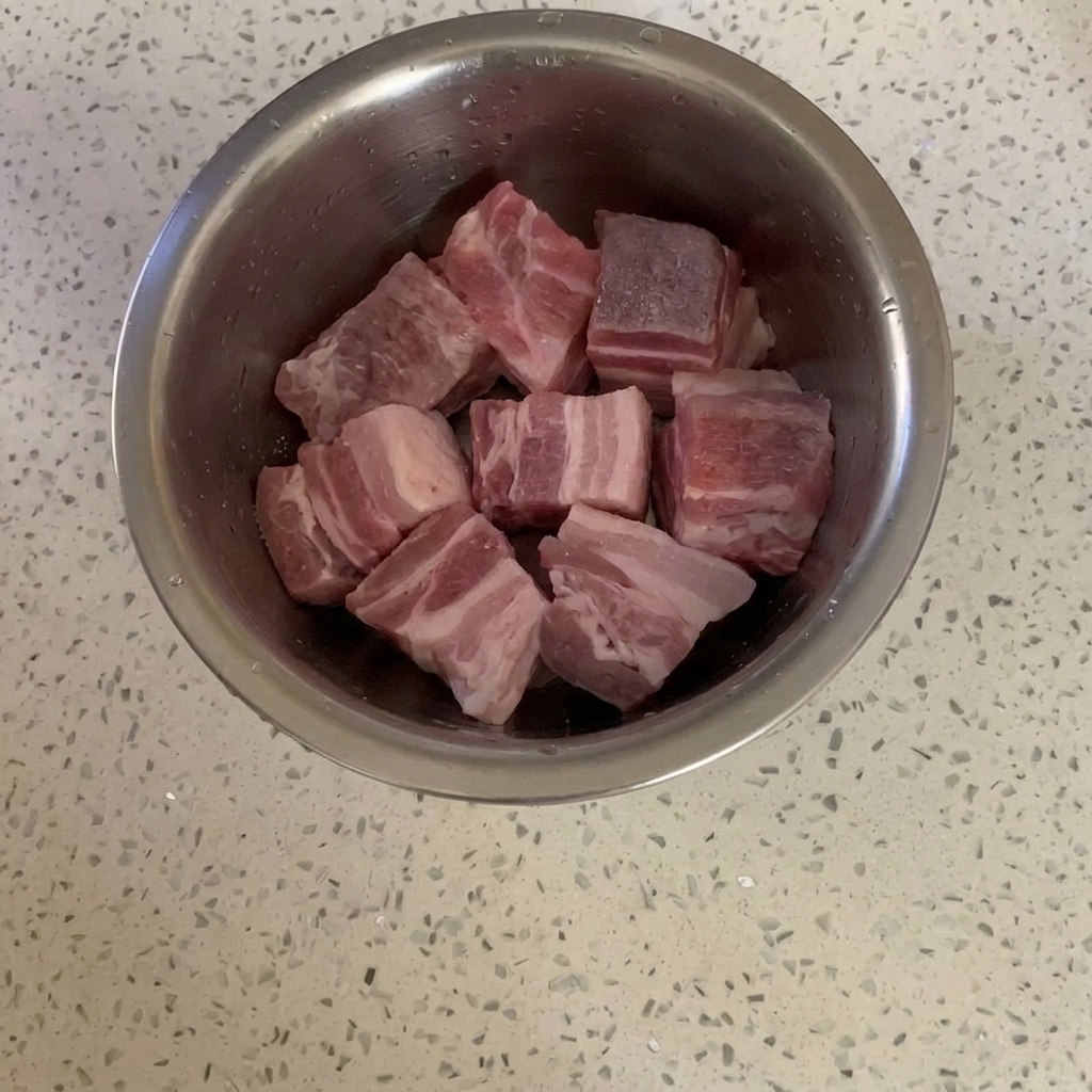 ボウルの中でグラニュー糖がまぶされた豚バラ肉。