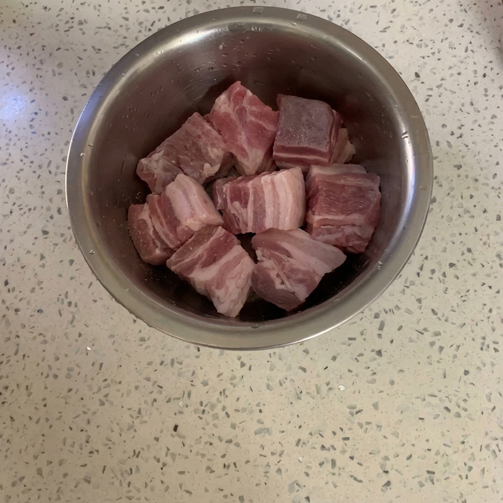 角切りの豚肉に粉末コショウが振りかけられている様子。