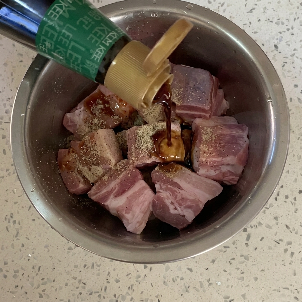 調味された豚肉に、ボトルから醤油が注がれている様子。