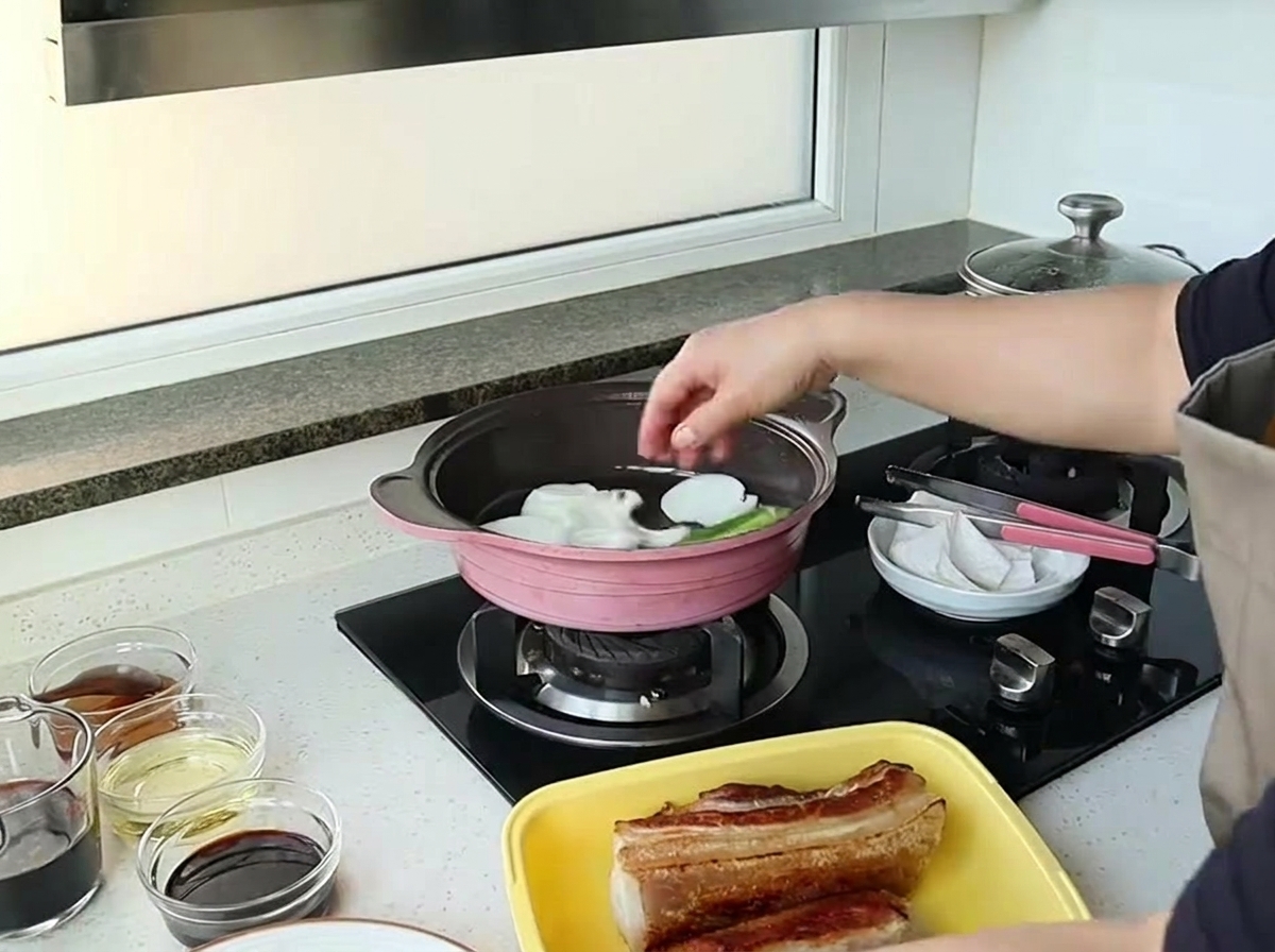 大きめに切った玉ねぎをピンクのフライパンに入れて炒めている様子
