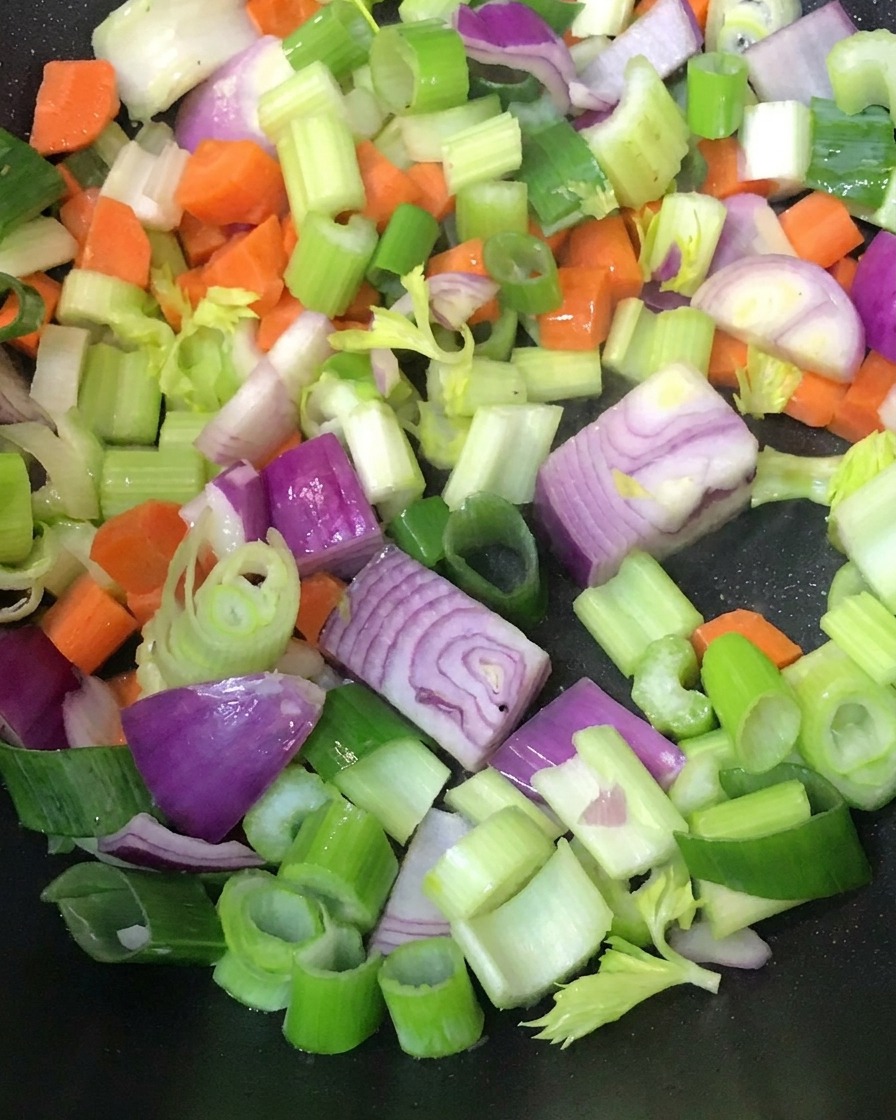 熱いフライパンで炒められている刻んだ野菜。