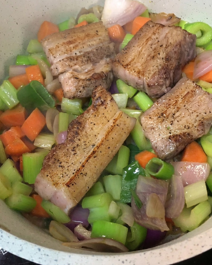 炒めた野菜をベースにして、その上に焼き色がついた豚バラ肉が並べられた鍋。