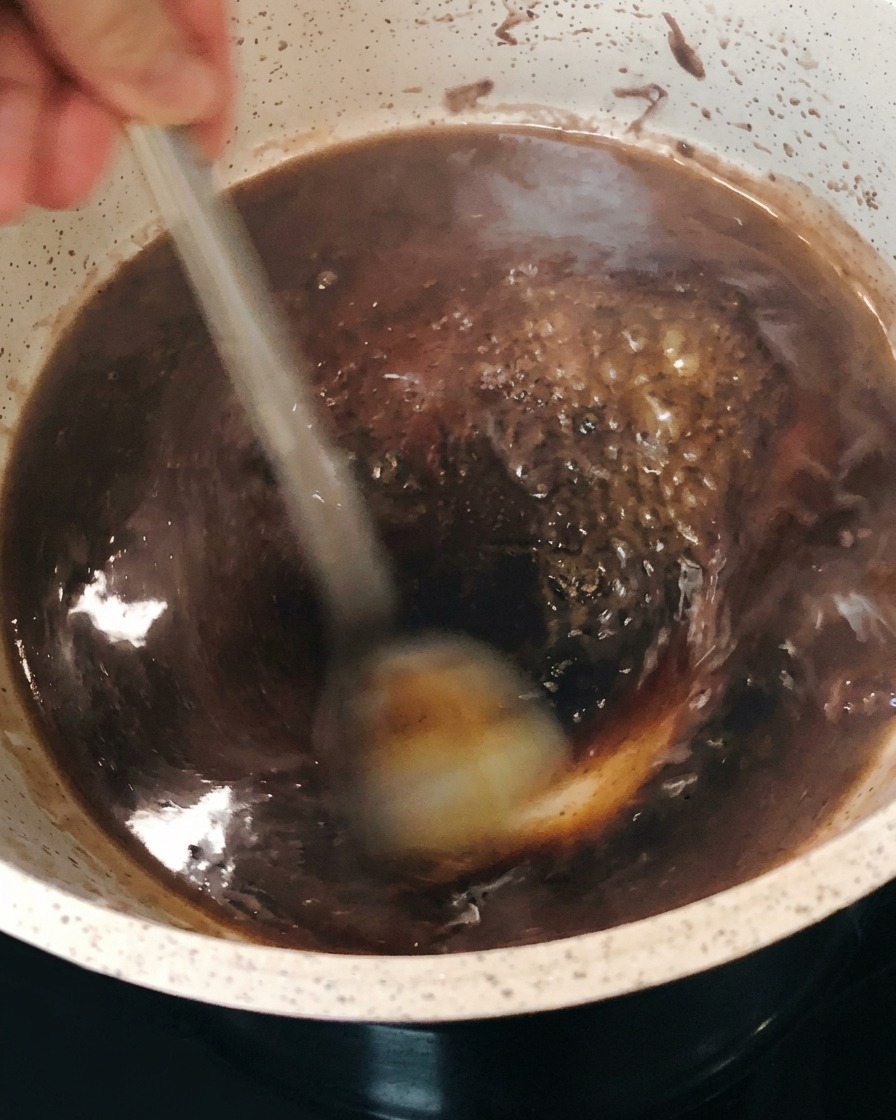 鍋の中で赤ワインソースが泡立ち、とろみがついていく様子。