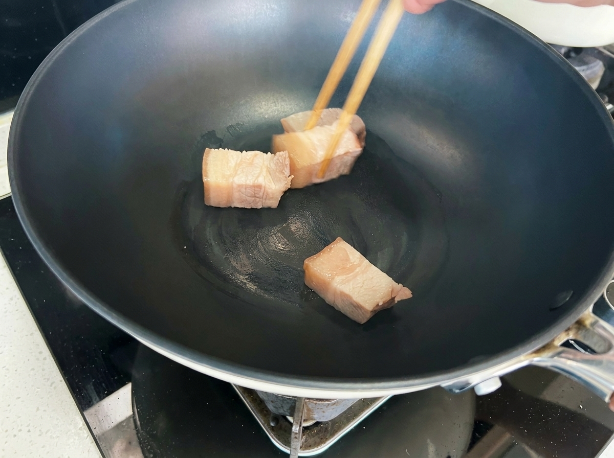 フライパンで豚肉の角切りをこんがりと焼き色がつくまで炒めている様子。