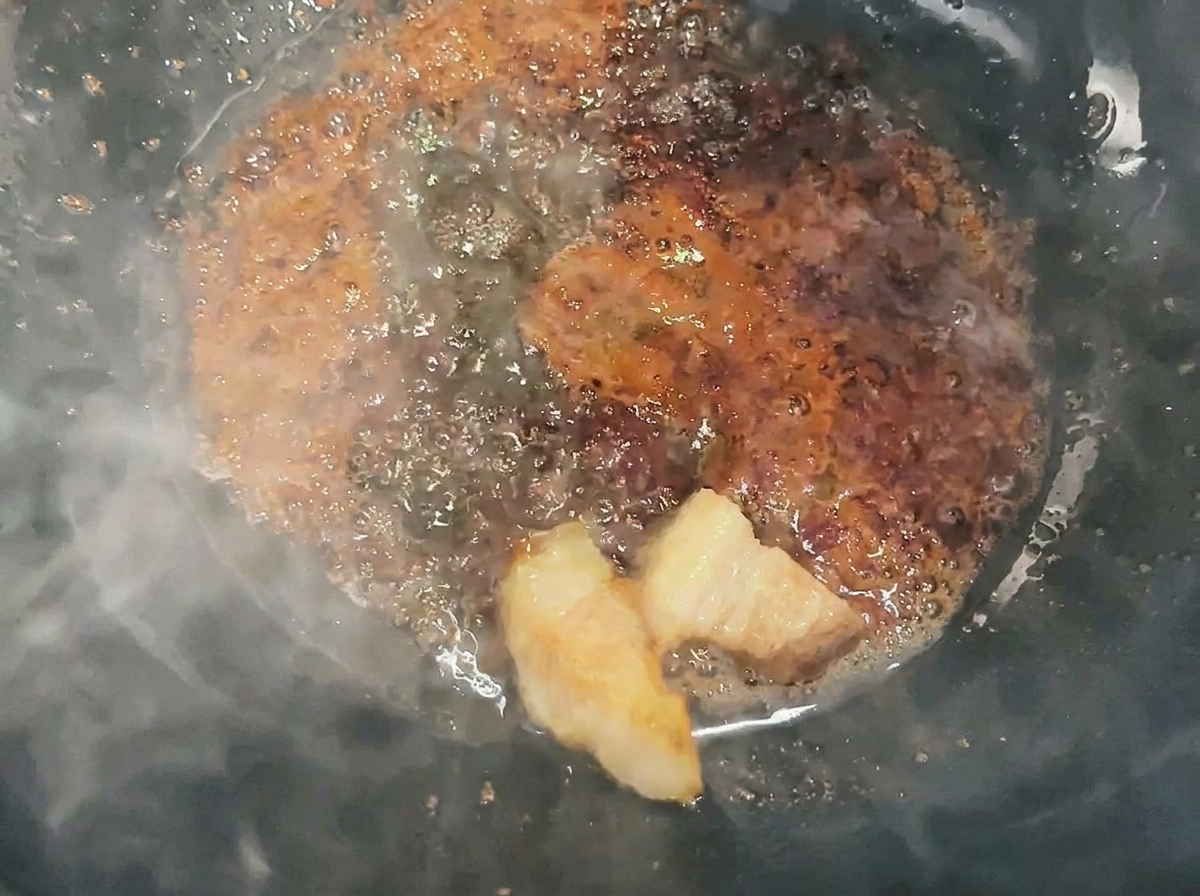 キャラメル状の砂糖で豚肉を艶やかにコーティングしている様子。