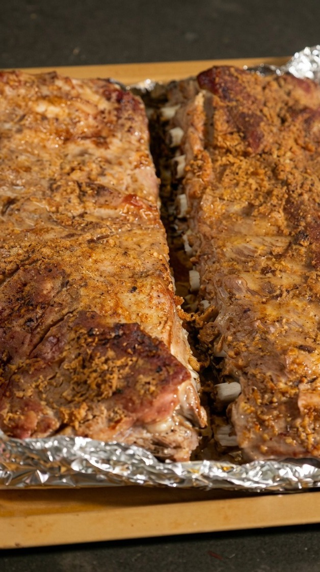 焼き上がったスペアリブのホイルを慎重に開き、中からしっとりとした肉が現れている様子。