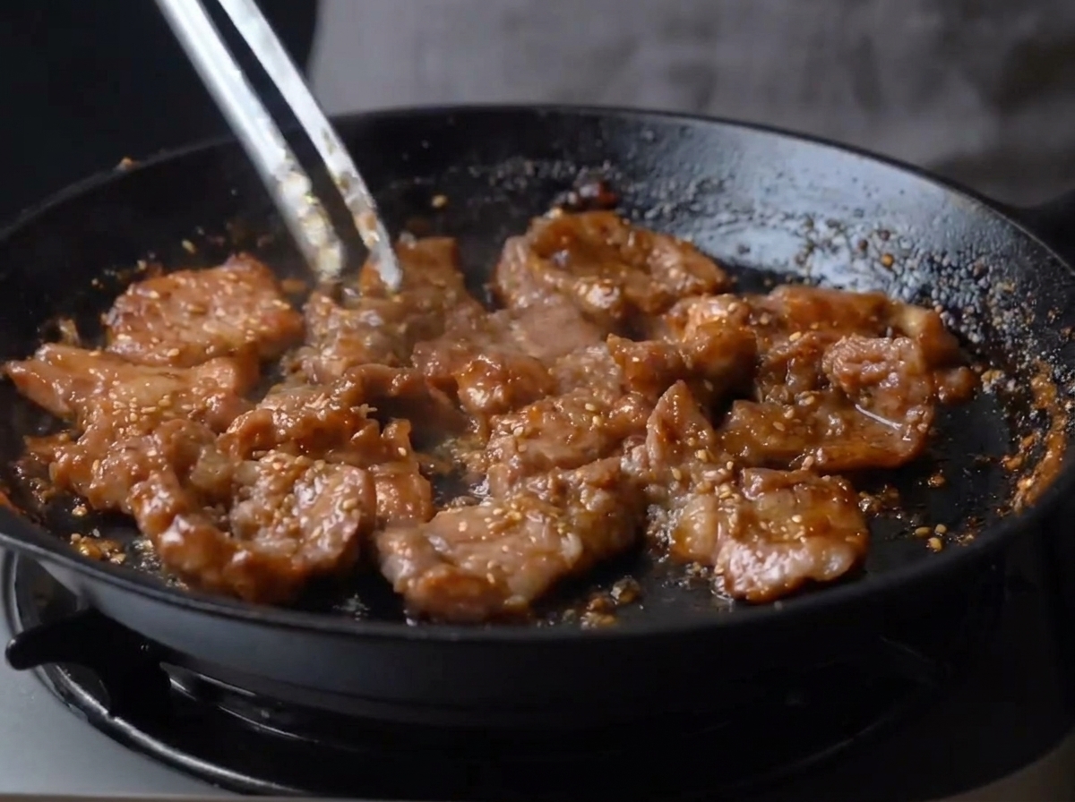 フライパンの中でタレが濃厚に絡まった、ツヤのある豚肉炒め。