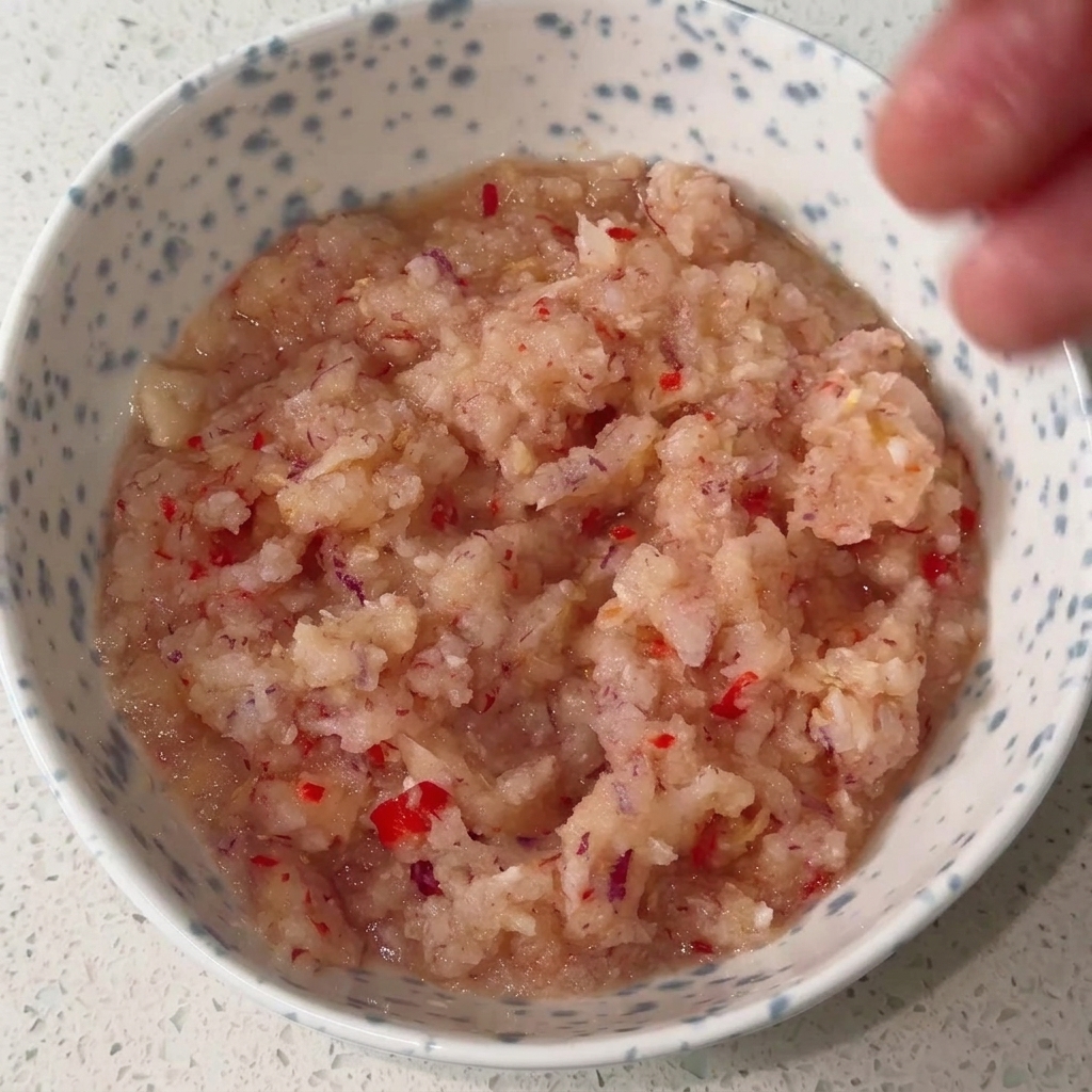 ペースト状にした香味野菜と各種調味料をボウルで混ぜ合わせ、真っ赤なタレを作っている様子