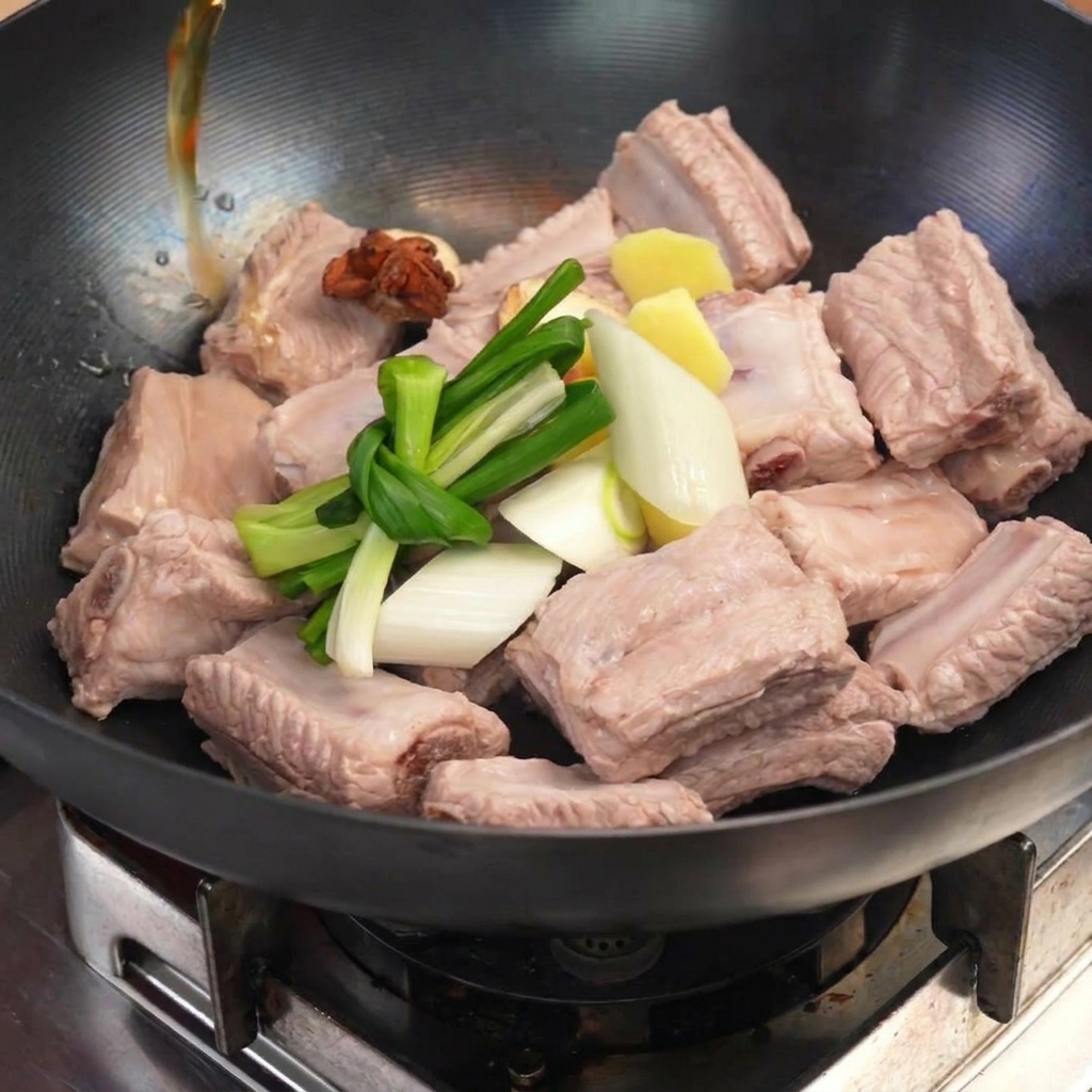 下茹でした豚肉に結んだ長ねぎ、生姜、八角を乗せ、お湯を注いでいる様子。