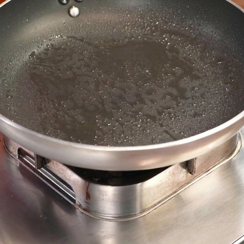 トッポギを詰めたスペアリブを、熱したフライパンで肉の面を下にして焼いている様子。