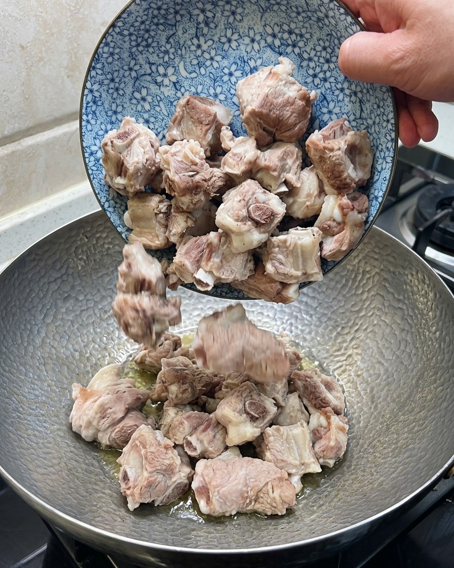 豚肉と生姜、八角、唐辛子を中華鍋で炒めている様子