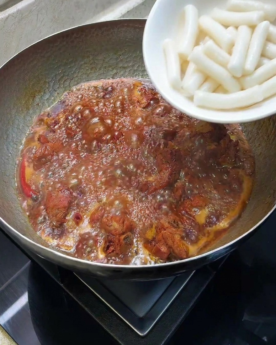 煮込んでいる鍋に白い餅を投入している様子