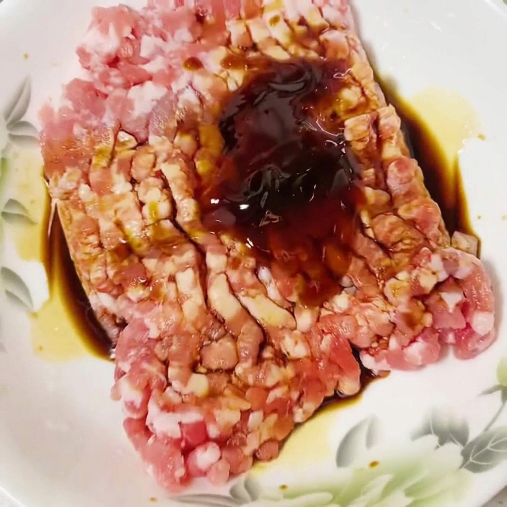 生肉のタネに鶏がらスープの素を振りかけている様子。